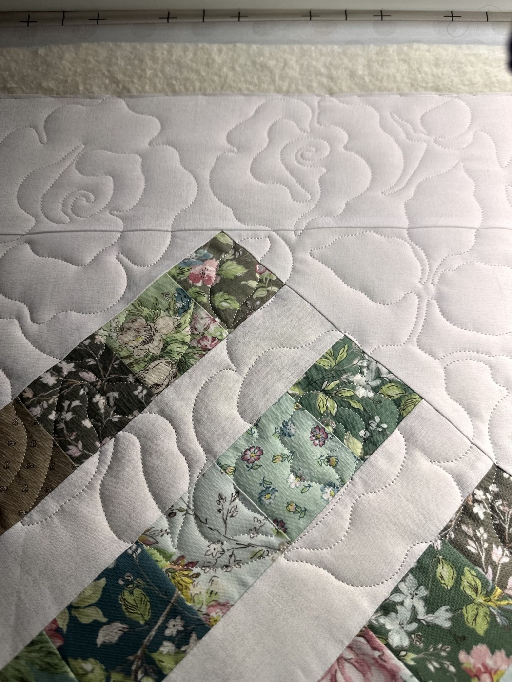 Soft quilting curves around green patchwork